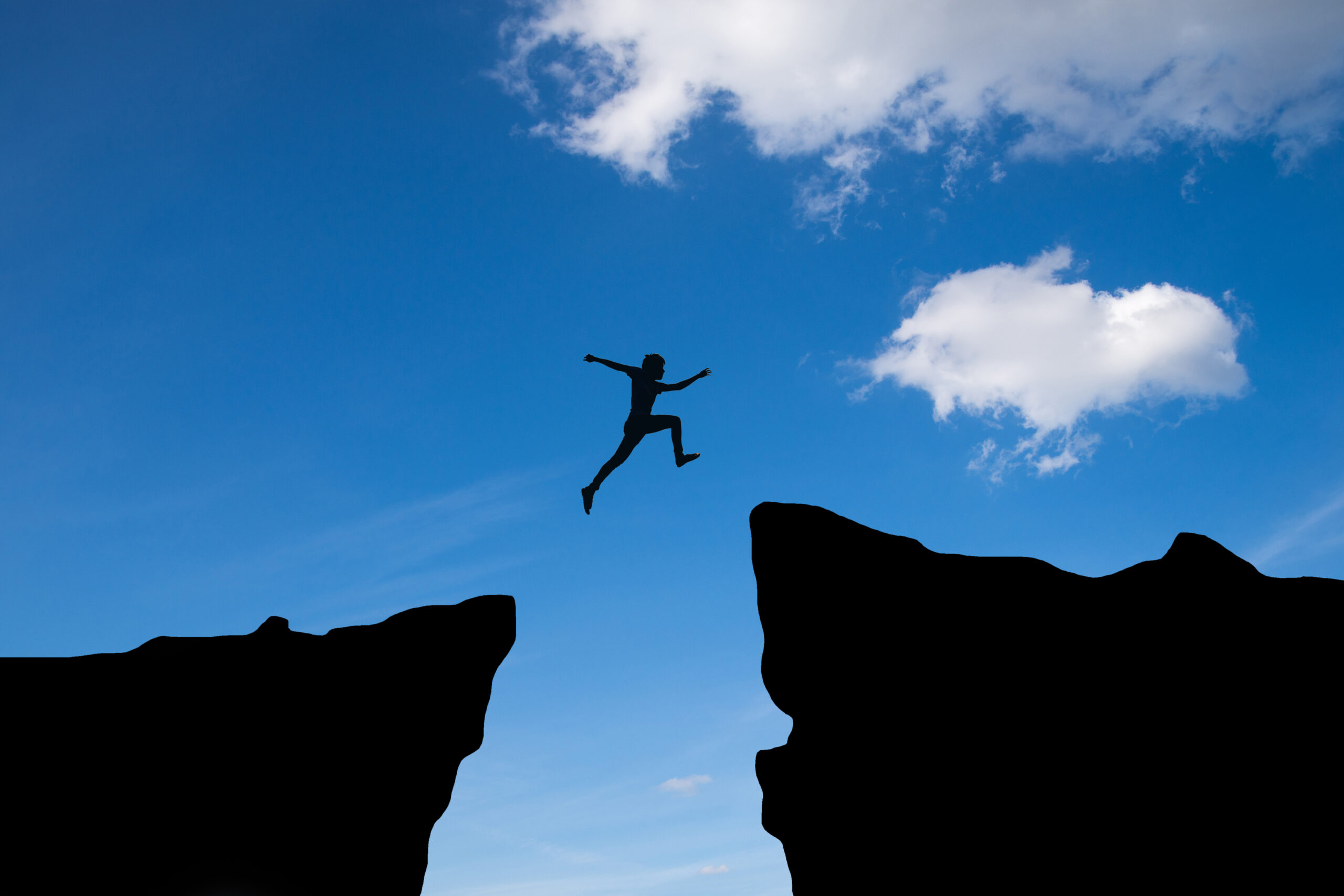 Man jump through the gap between hill.man jumping over cliff on blue sky ,Business concept idea